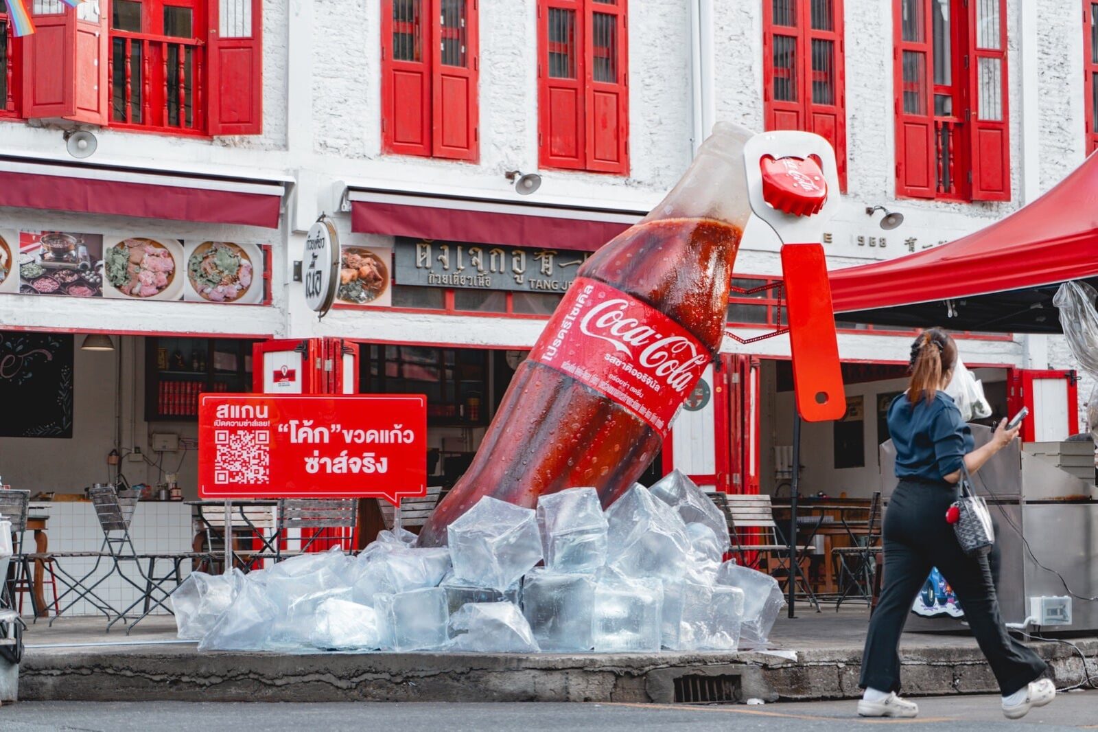 Giant Coca-Cola glass bottle pouring into ice, a Chinatown street installation in daylight