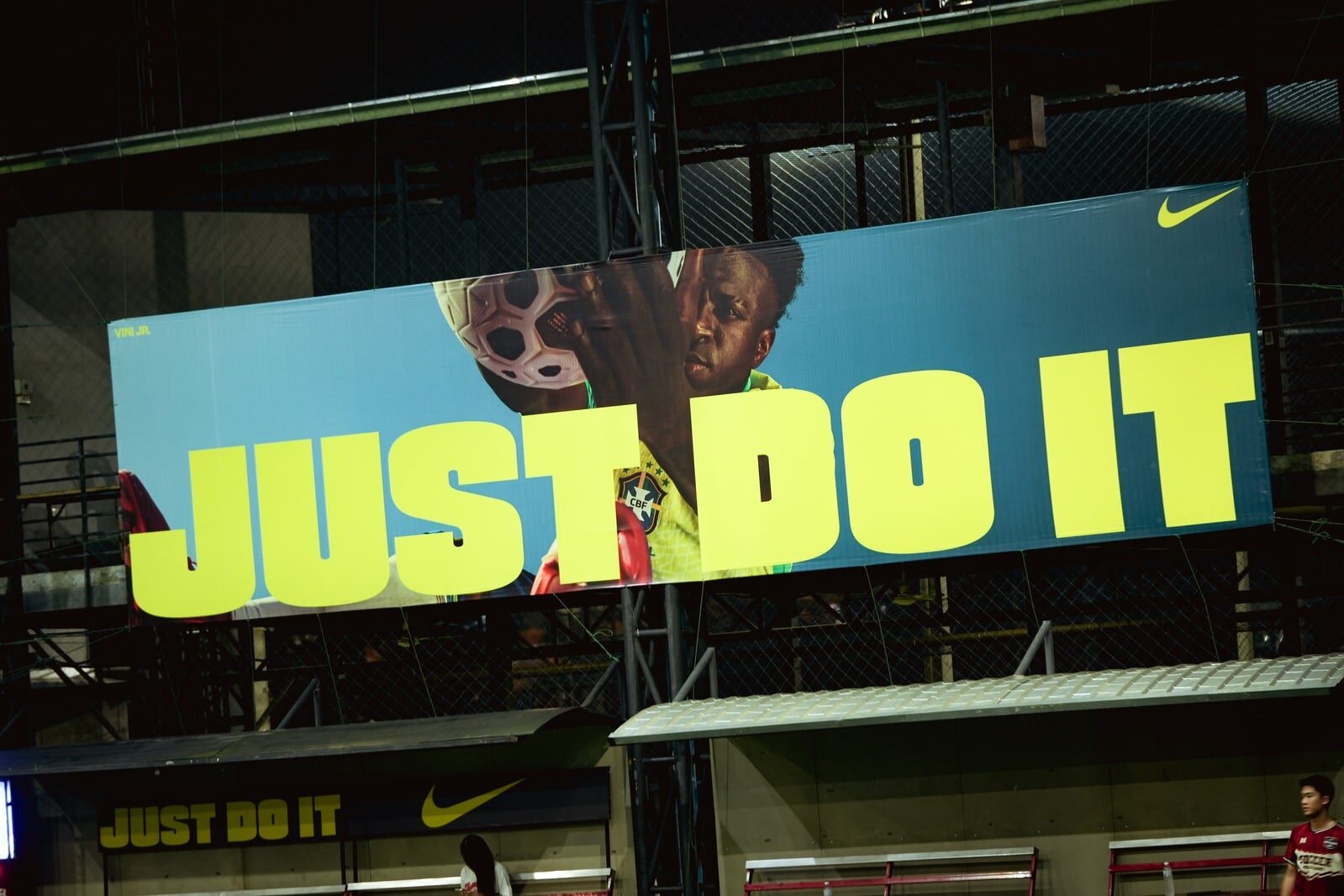 Nike JUST DO IT billboard in lime type over blue at a floodlit futsal pitch