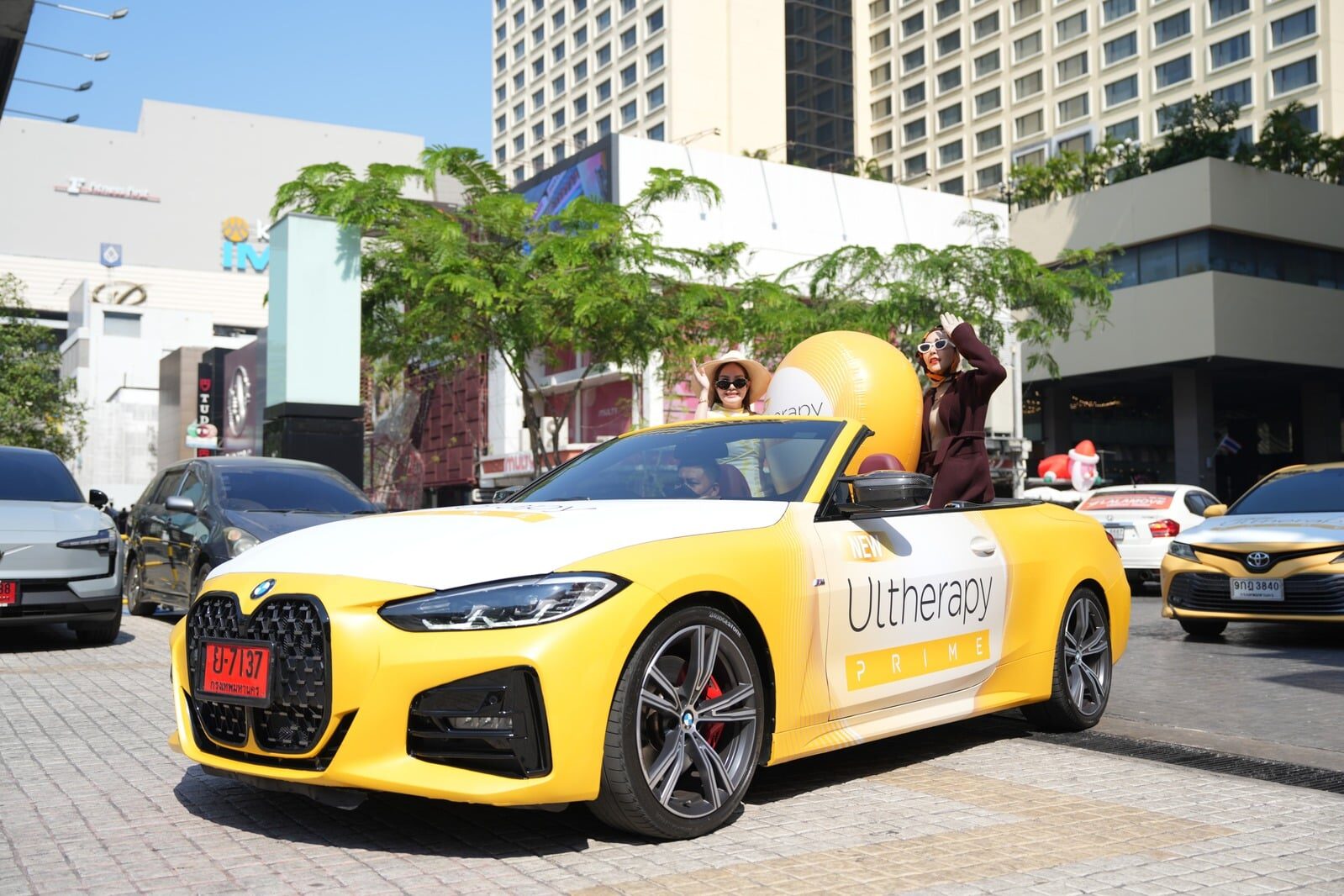 Yellow Ultherapy-wrapped BMW convertible on a Bangkok roadshow in daylight