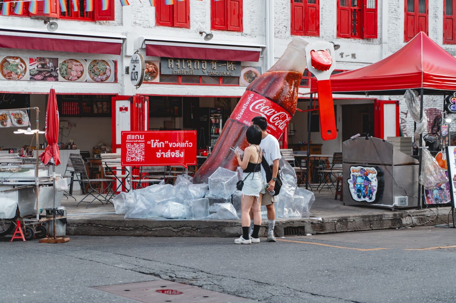 Giant Coca-Cola bottle pouring into ice, a Chinatown street installation in daylight