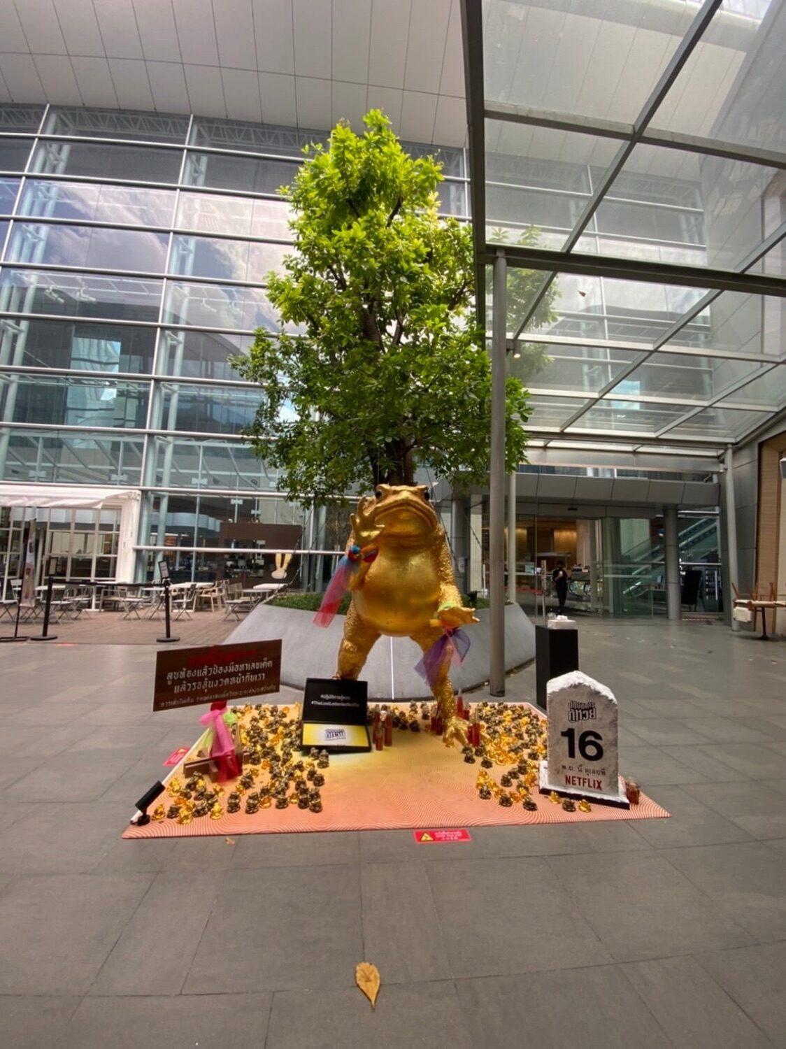 Netflix The Lost Lotteries golden frog installation with a live tree at a mall entrance